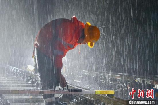 图为南铁九江桥工段共青城线路车间作业人员冒雨检查线路轨距水平。陈果 摄